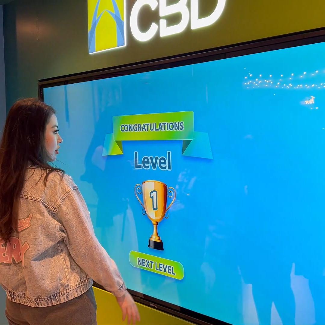 People playing a multi-level interactive financial literacy game at a brand activation event in Dubai, learning how to save and invest money.